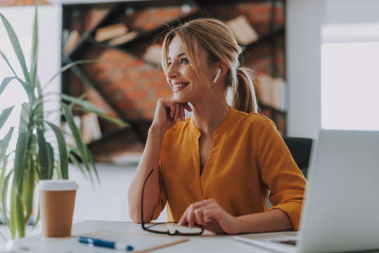 Cheerful woman wearing wireless earphones and smiling