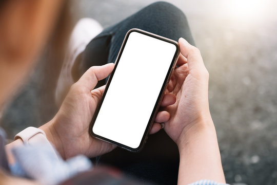 Top view Woman sitting and holding blank screen mock up mobile phone