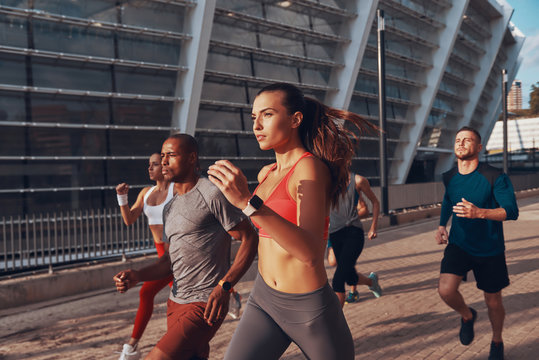 Group of young people in sports clothing jogging together outdoors