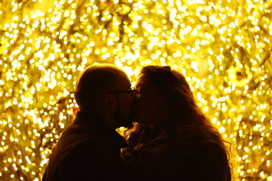 Silouette of man and woman in love kissing in front a Christmas Tree