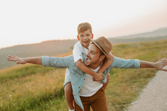 A mature father standing and holding a toddler son, having fun.