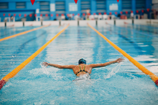 Young woman swimmer swims in swimming pool