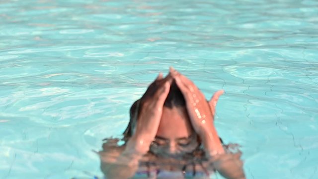 4K slow motion footage of young woman comes up from swimming pool