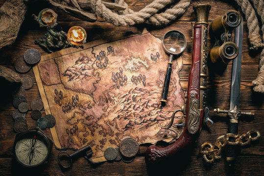 Pirate treasure map and human skull on brown wooden table closeup background.