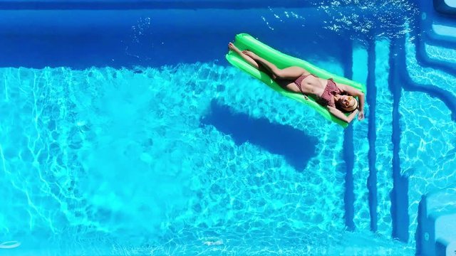 top view of girl relaxing on pool float in swimming pool in summer