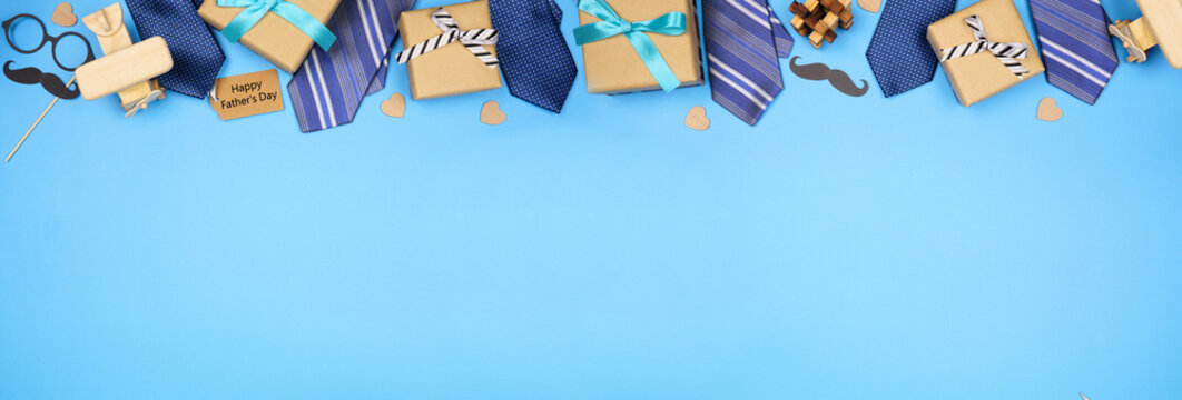 Happy Fathers Day gift tag with long border of ties, gifts and games on a blue banner background. Above view with copy space.