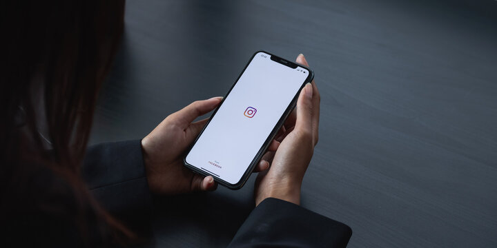 CHIANG MAI, THAILAND - APR 6 2021: Woman hand holding iphone with logo of instagram application. Instagram is largest and most popular photograph social networking