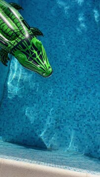 funny footage of a inflatable green crocodile swimming pool toy floating on the clean pool waves surface. Summer vacation concept 4K vertical footage for mobile devices usage