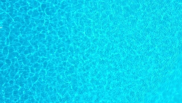 Blue water in the swimming pool with light reflections. Aerial footage