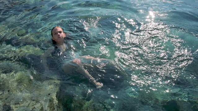 Happy girl swimming on the lake and shaking legs. 4k footage UHD 3840x2160 
