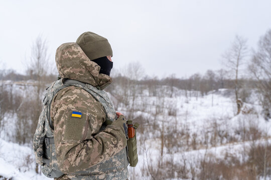 a Ukrainian military man in winter uniform, body armor and with a weapon is on combat duty. protective equipment of a soldier. infantryman with machine gun and ammunition at war in winter