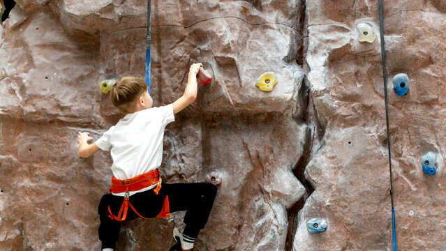 a boy or girl on a climbing wall climbs the wall of a climbing wall