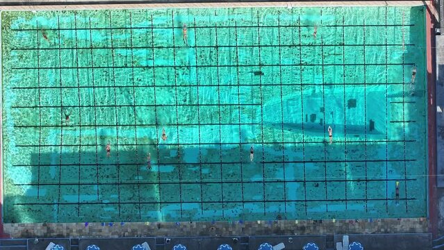 Top down aerial footage of a large swimming pool with many people doing morning exercises in Rio de Janeiro.