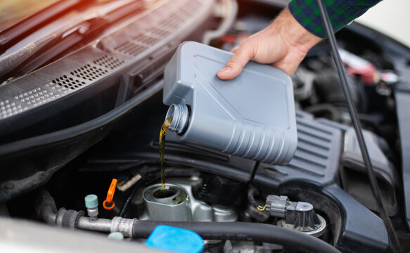 Close up photo of car mechanic or repairman is changing engine oil. Refueling and pouring oil into the engine motor car. Transmission and maintenance gear