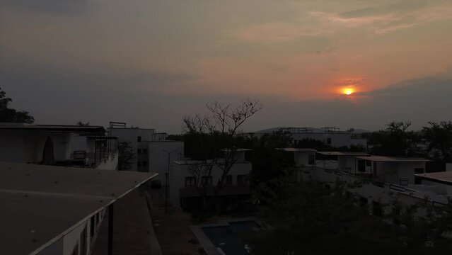 Human been in roof garden in a dramatic twilight sunset over white houses, Tilt up camera