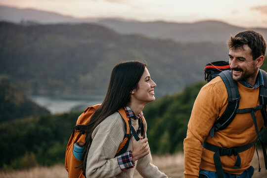 Loving mid aged couple with a backapacks hiking on the hills together