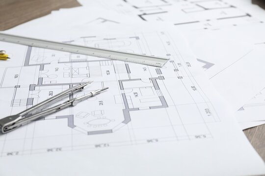 Different architectural drawings, divider and ruler on table, closeup