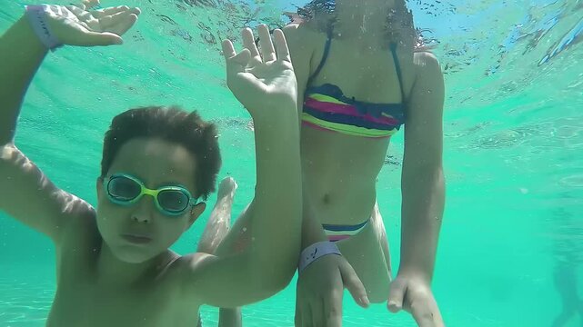 Happy girl and boy swimming under water. High quality 4k footage