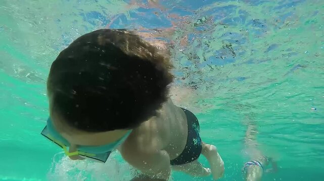 The boy is spinning under the water in the pool. High quality 4k footage