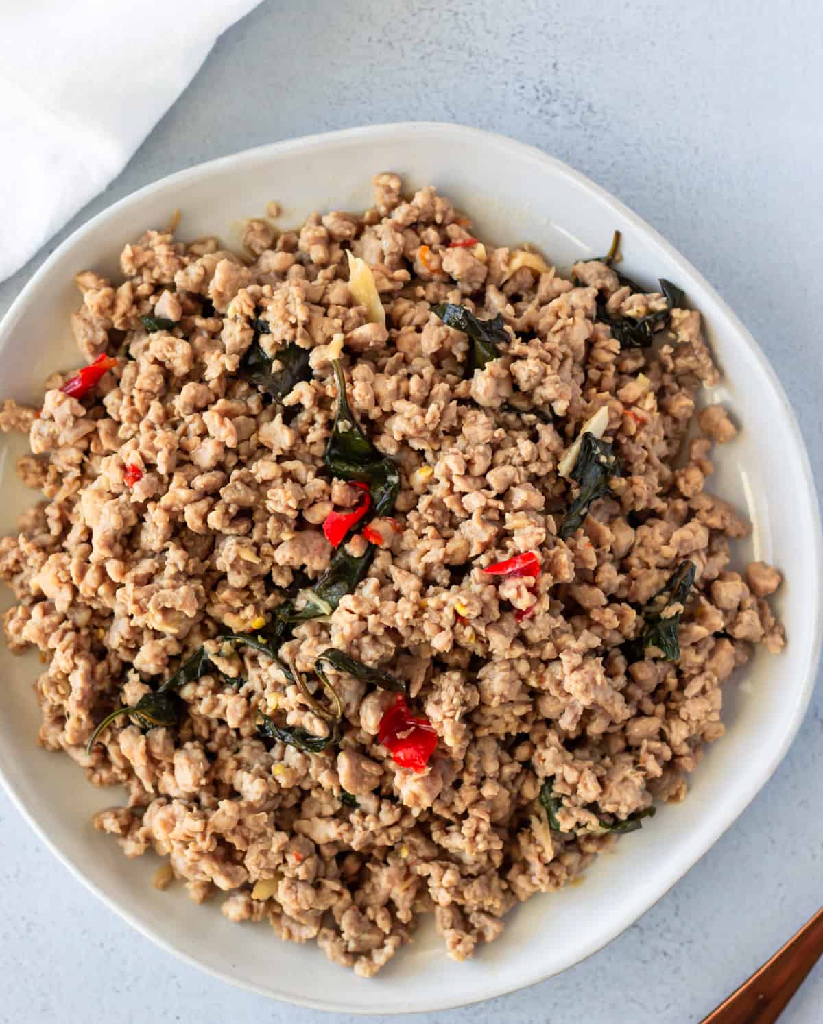 Overhead view of pad kra pao moo on a white plate.