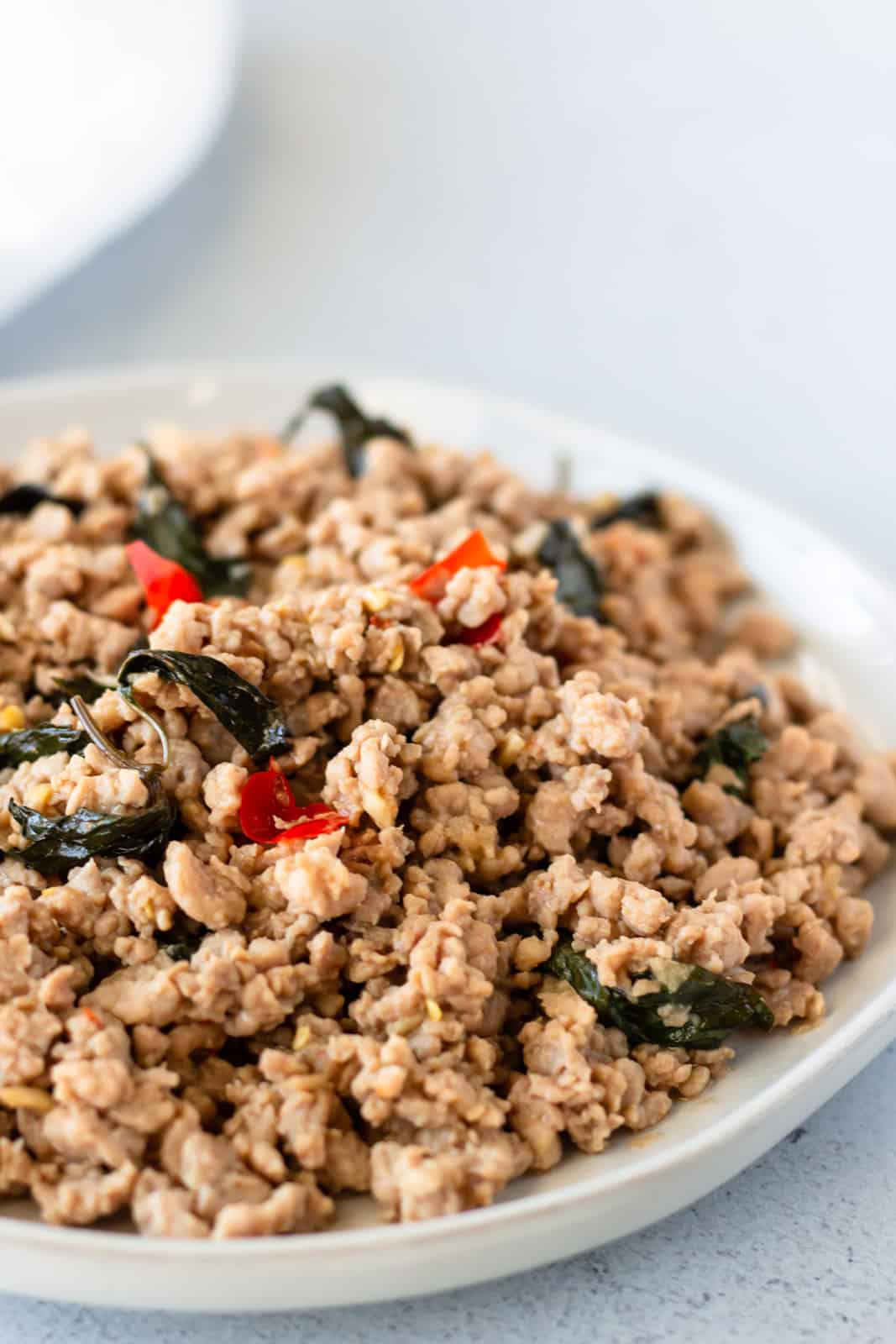 Up close view of Pad kra pao moo on a white plate.