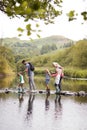 Family Crossing River Whilst Hiking In UK Lake District