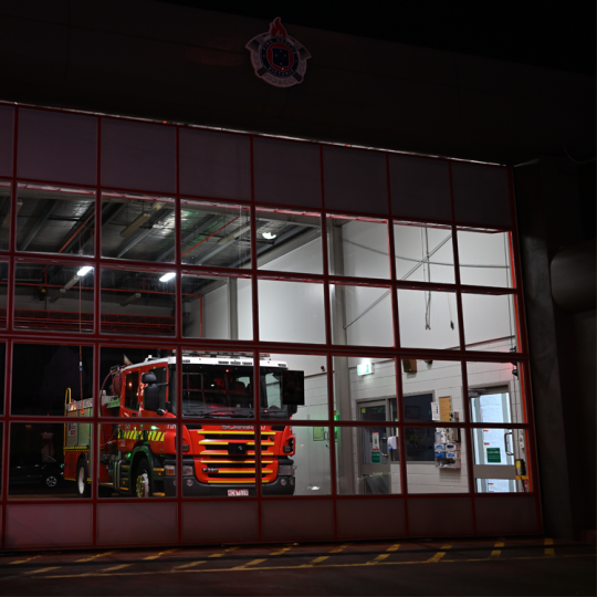 A fire truck inside a fire station at night.