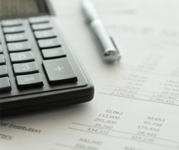 Close-up of a calculator and a pen sitting on top of some accounting documents.