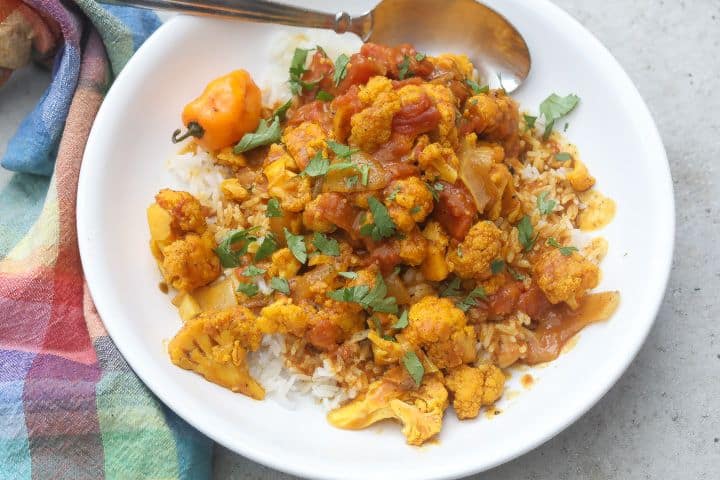 yellow cauliflower florets over rice topped with curry sauce