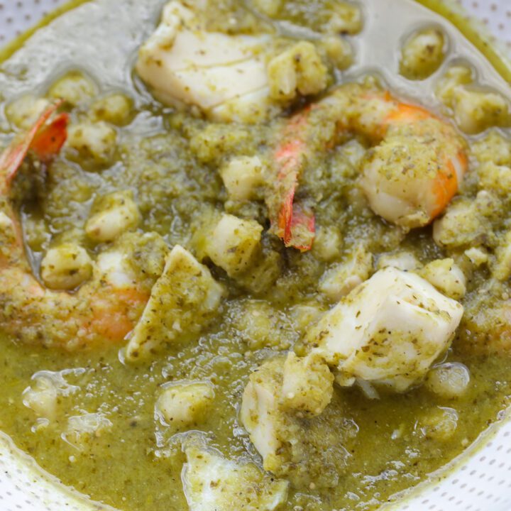 seafood posole verde in a white bowl with avocado