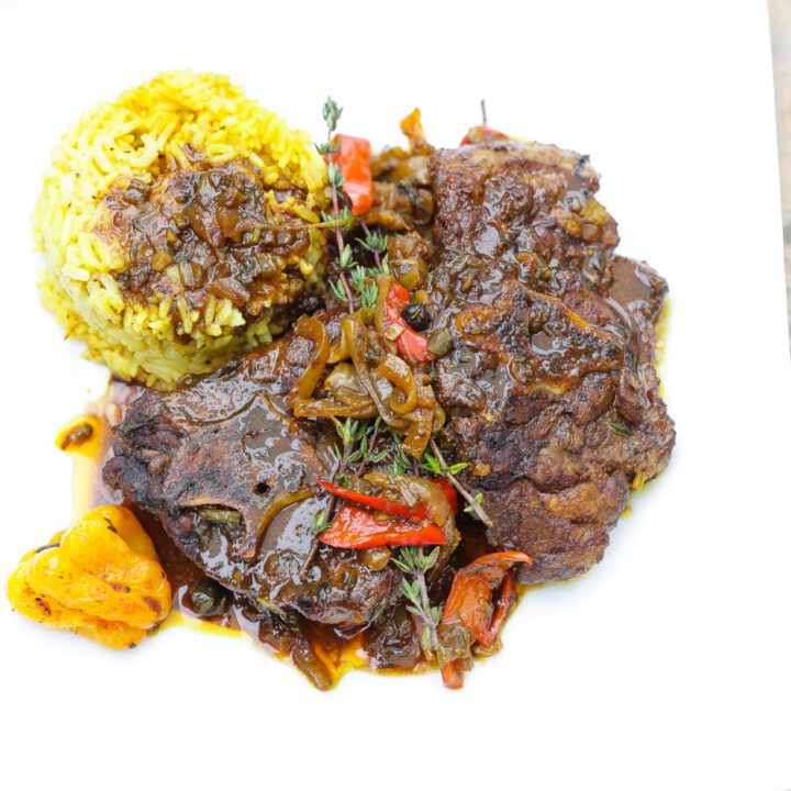 brown stew lamb necks with rice on white plate