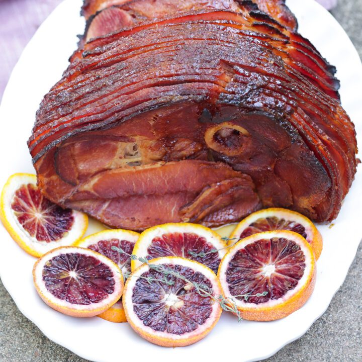 A sliced maple glazed ham placed on a white platter.