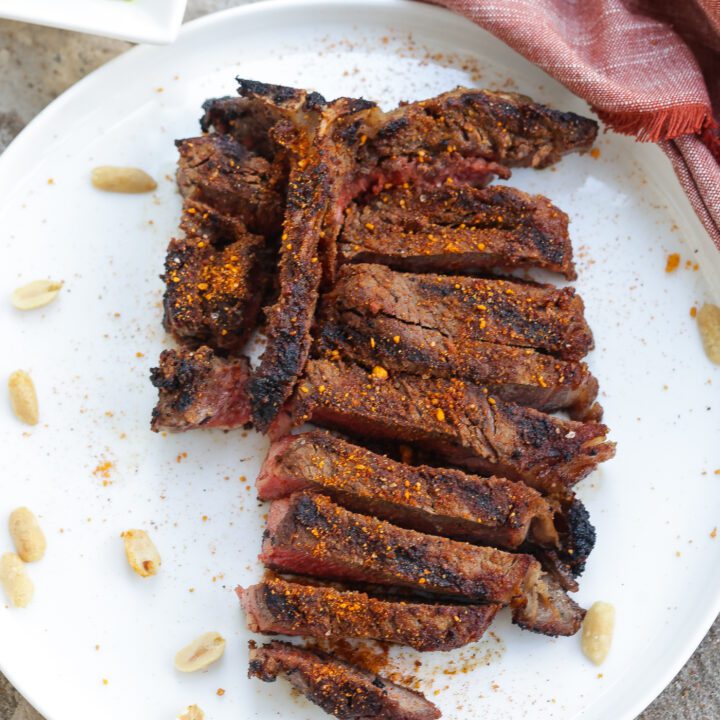 grilled t-bone steak with suya spice on white plate