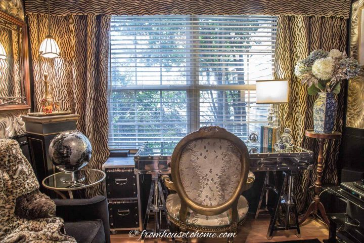 Small black and gold home office with desk facing the window