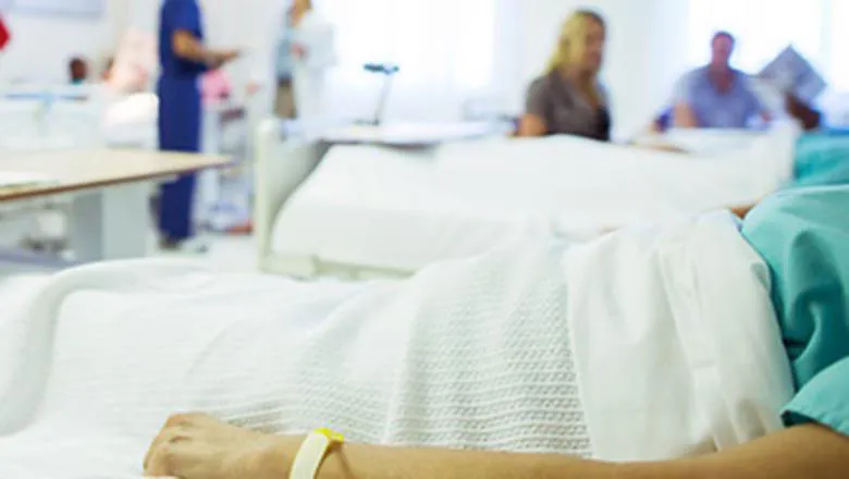 A patient lies in a hospital bed, their head is out of frame