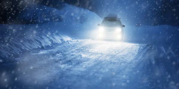 Car driving on a snow packed road at night