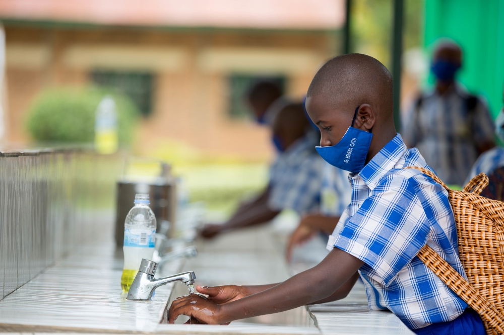 Children wash their hands before entering class at Groupe Scolaire Remera Catholique. Dan Nsengiyumva