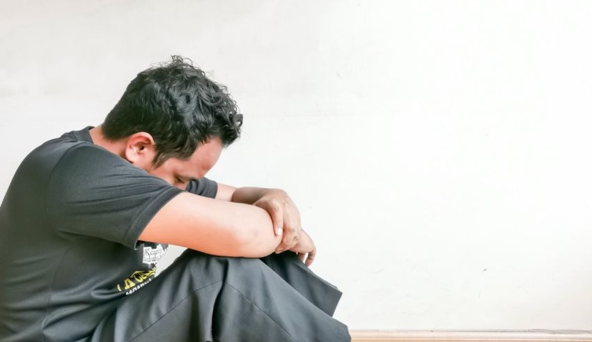 A man sitting on the floor with his hands on his knees.