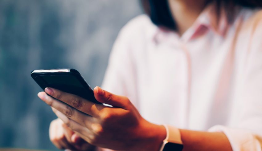 A woman is holding a cell phone while sitting at a table.