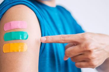 Man points to three bandages on arm