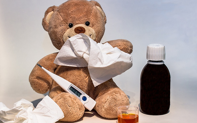 Ein Teddy-Bär der ein Tempo und ein Fieberthermometer in der Hand hat