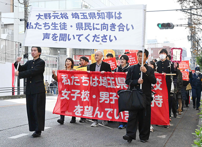 横断幕を掲げ行進する参加者ら＝26日午後、さいたま市浦和区