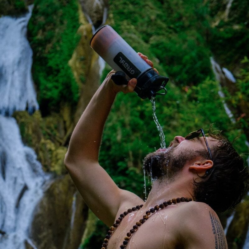 backpacker drinking using grayl geopress filter bottle