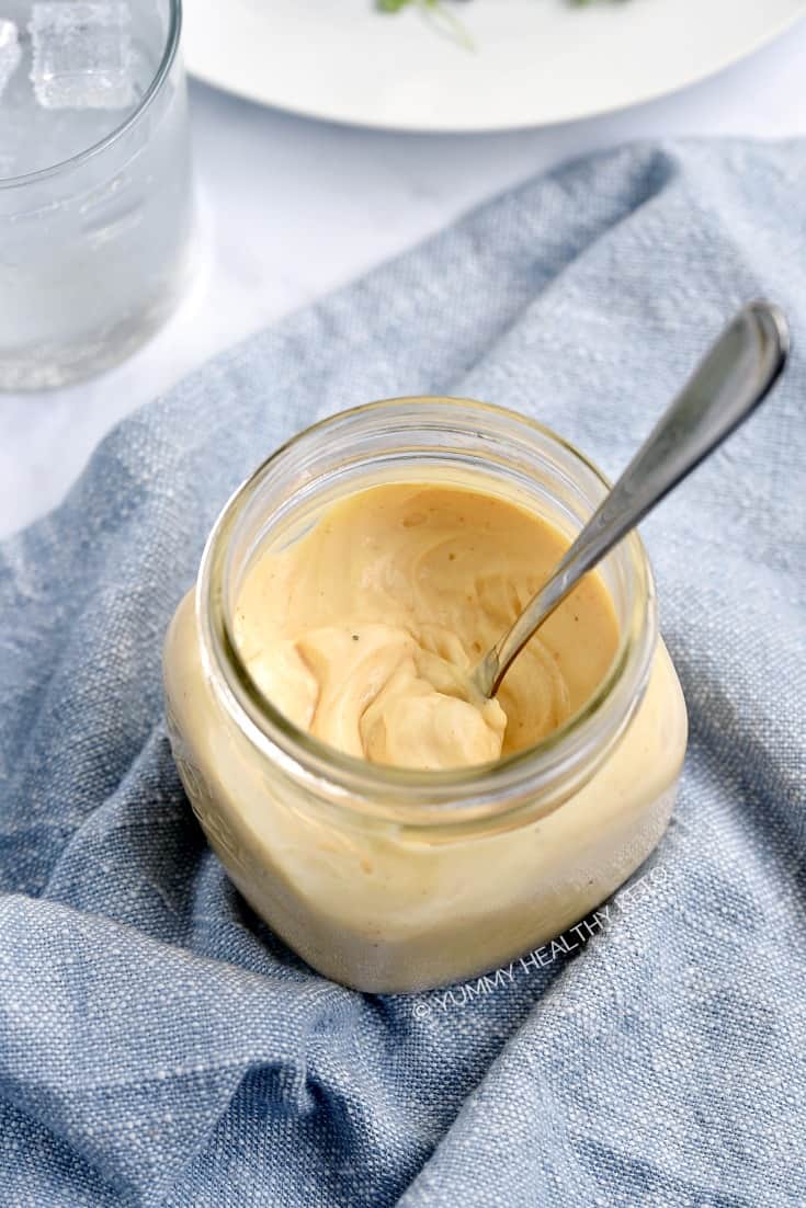 Looking down on a jar of easy blender baconnaise that is sitting on a blue napkin